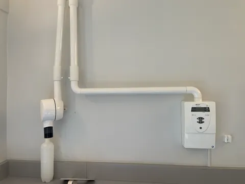 Wall-mounted intraoral X-ray unit with an articulated arm and exposure control.