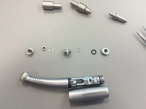 Disassembled dental handpiece and components on a worktop.