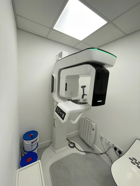 Installed panoramic dental imaging unit with a black front panel and green indicator light.