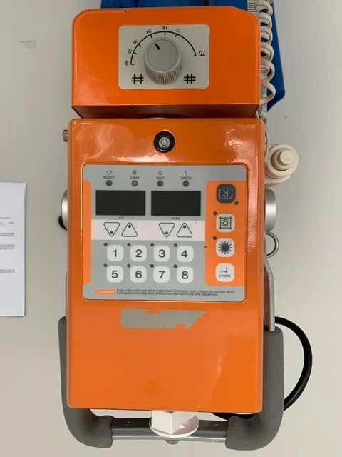 Orange portable X-ray unit with its exposure controls.