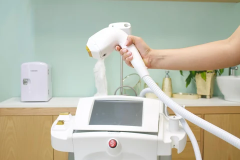 Frontal view of an aesthetic treatment device with its handheld applicator.